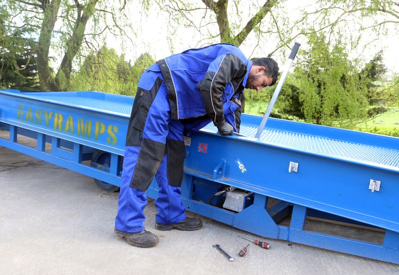 close-up on the man wearing blue work clothes servicing the loading ramp, loading ramps service and support