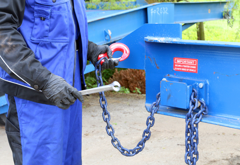 close-up on the man holding chain with red hook, loading ramps service and support