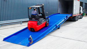 the red forklift driving up on the blue loading ramp into the empty container, easyramps.co.uk - heavy-duty loading ramps uk